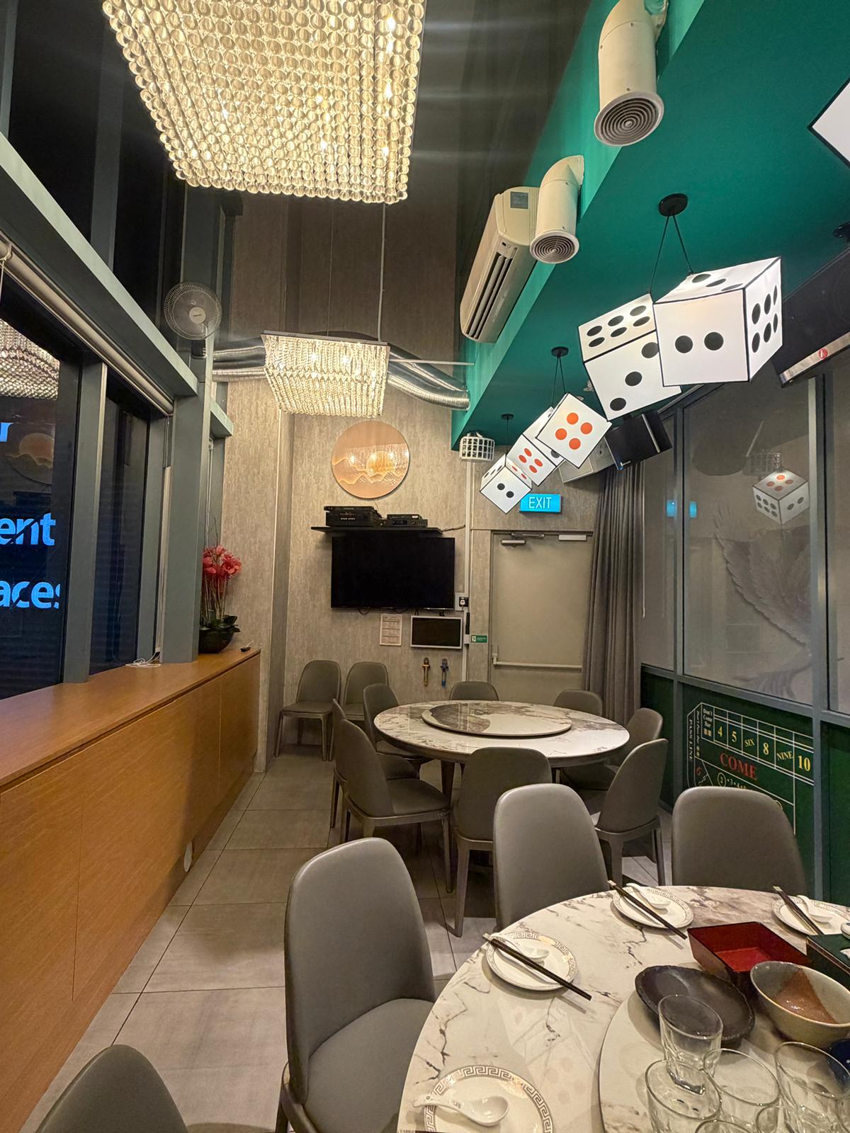 Modern restaurant interior with tables, chairs, and decorative dice on the ceiling in Clarke Quay.