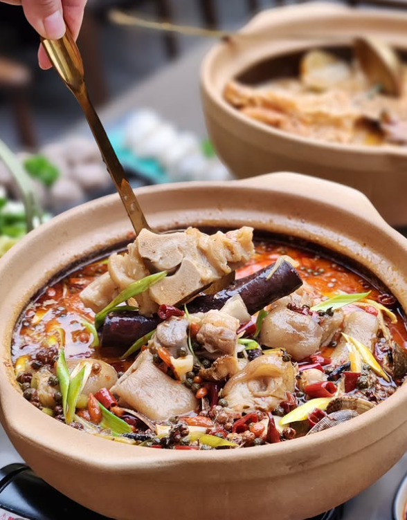 Spicy hotpot in a ceramic pot with a spoon in Er Dang Jia. 