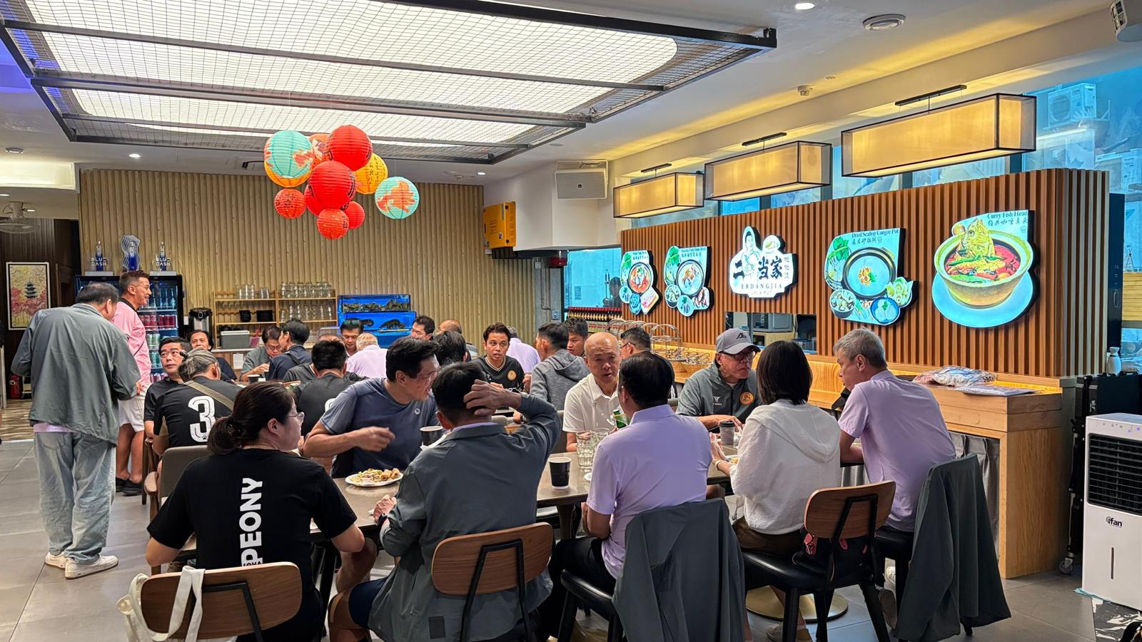 People dining and socializing in a modern restaurant with colorful wall art and balloons.
