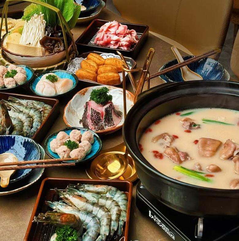 Diverse array of raw and cooked foods on a dining table with a hot pot in Clarke Quay.