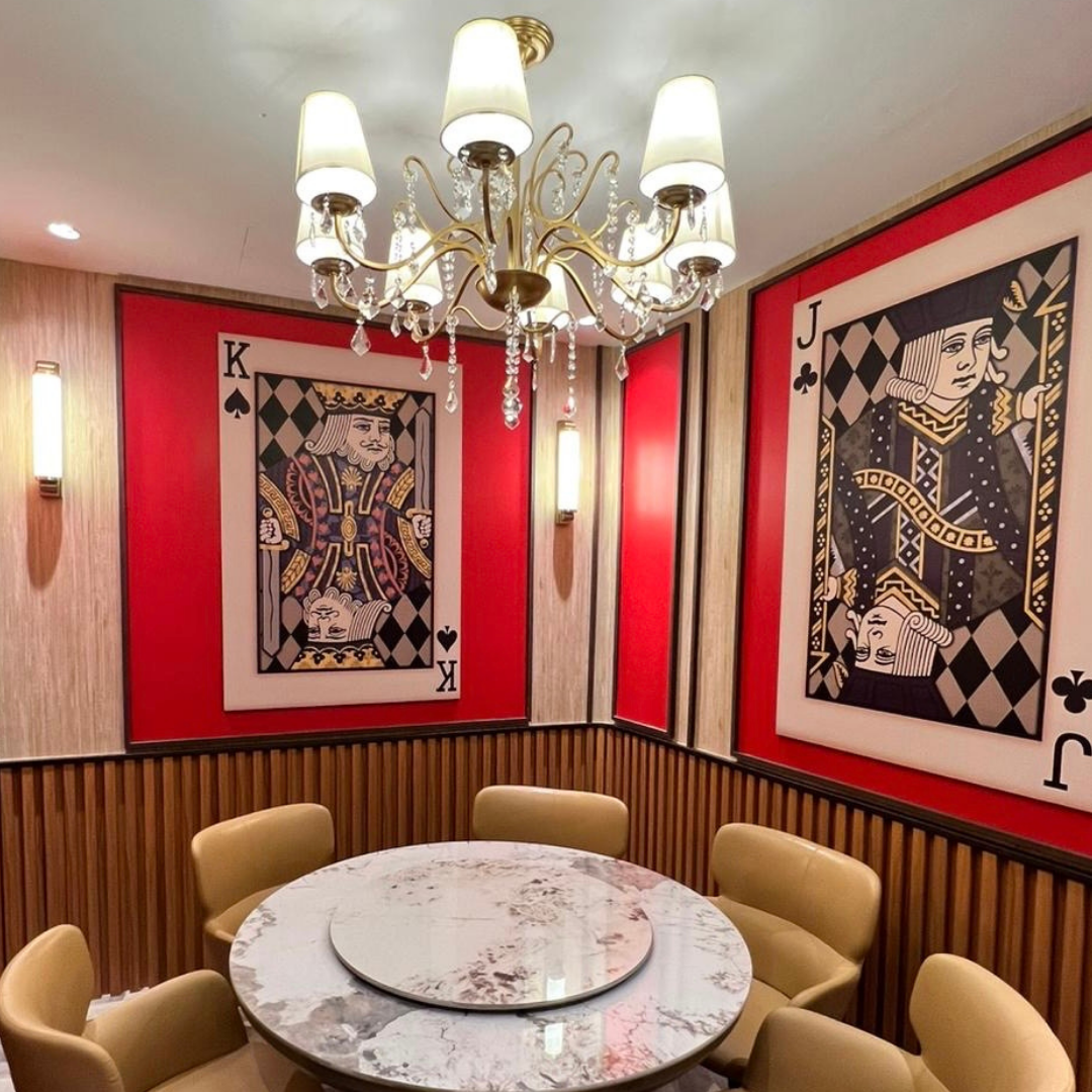 Dining room with playing card-themed wall art and a chandelier in Clarke Quay.