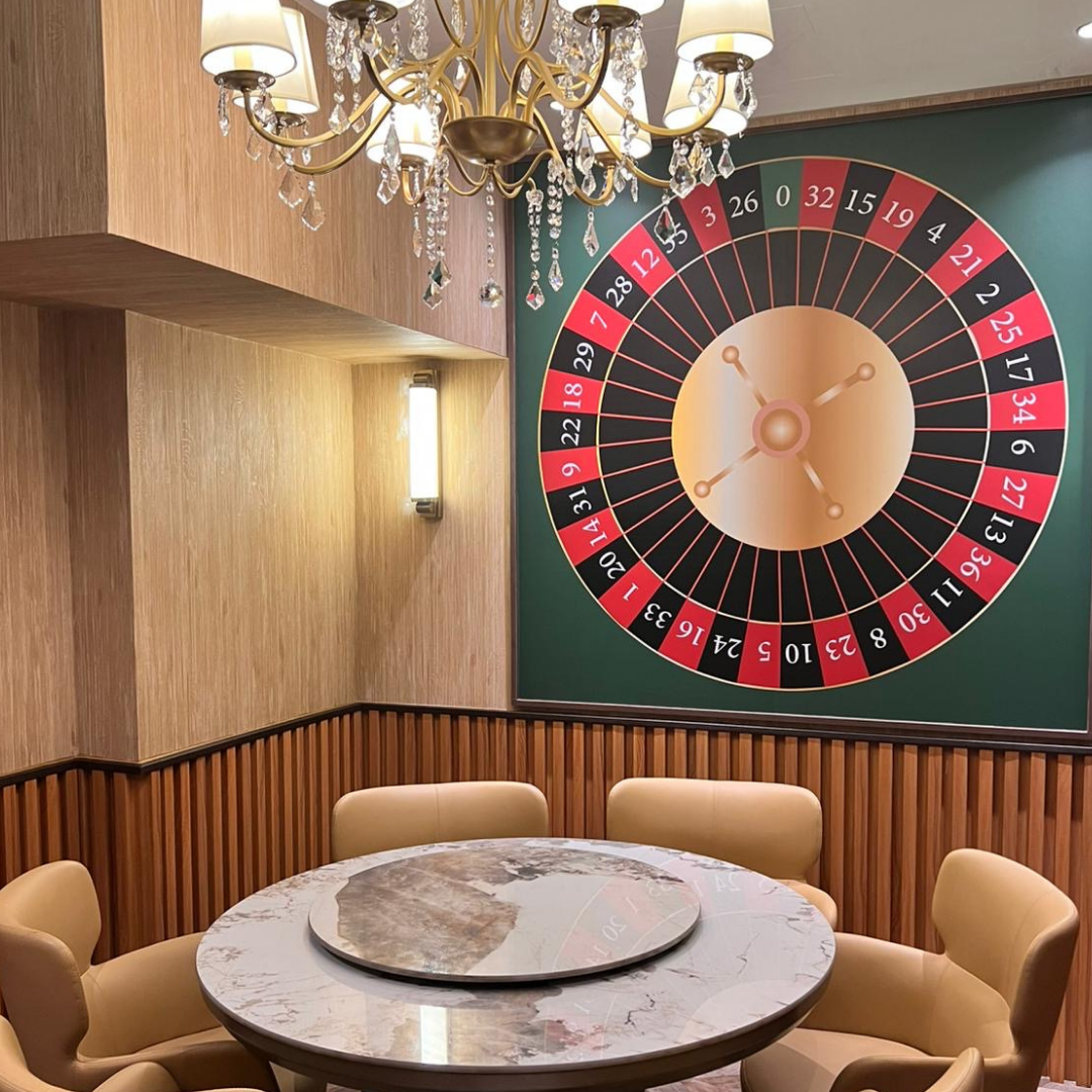 Casino-themed room with roulette wheel on the wall and marble table with chairs in Clarke Quay.