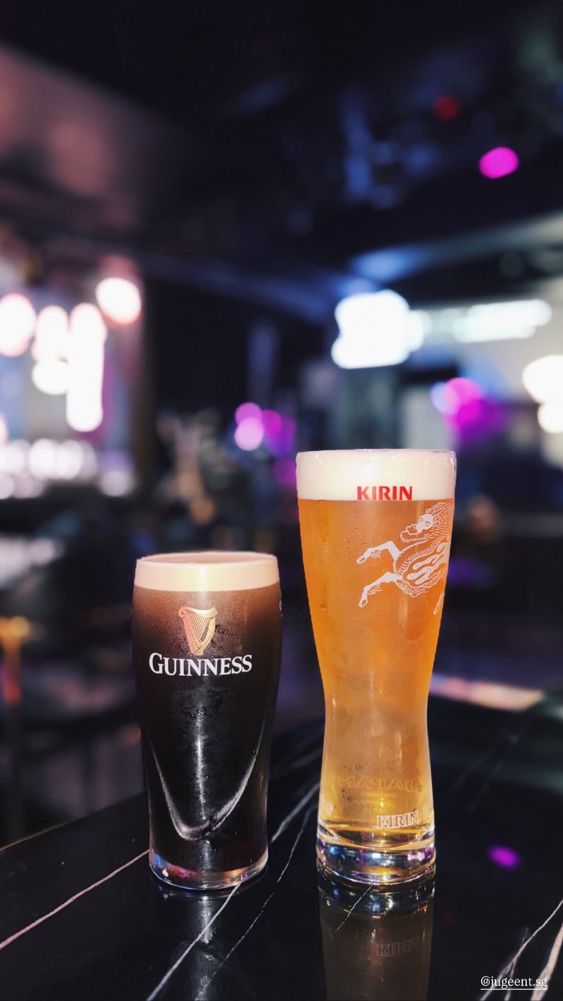 Two glasses of beer, one Guinness and one Kirin, on a bar counter in Clarke Quay.