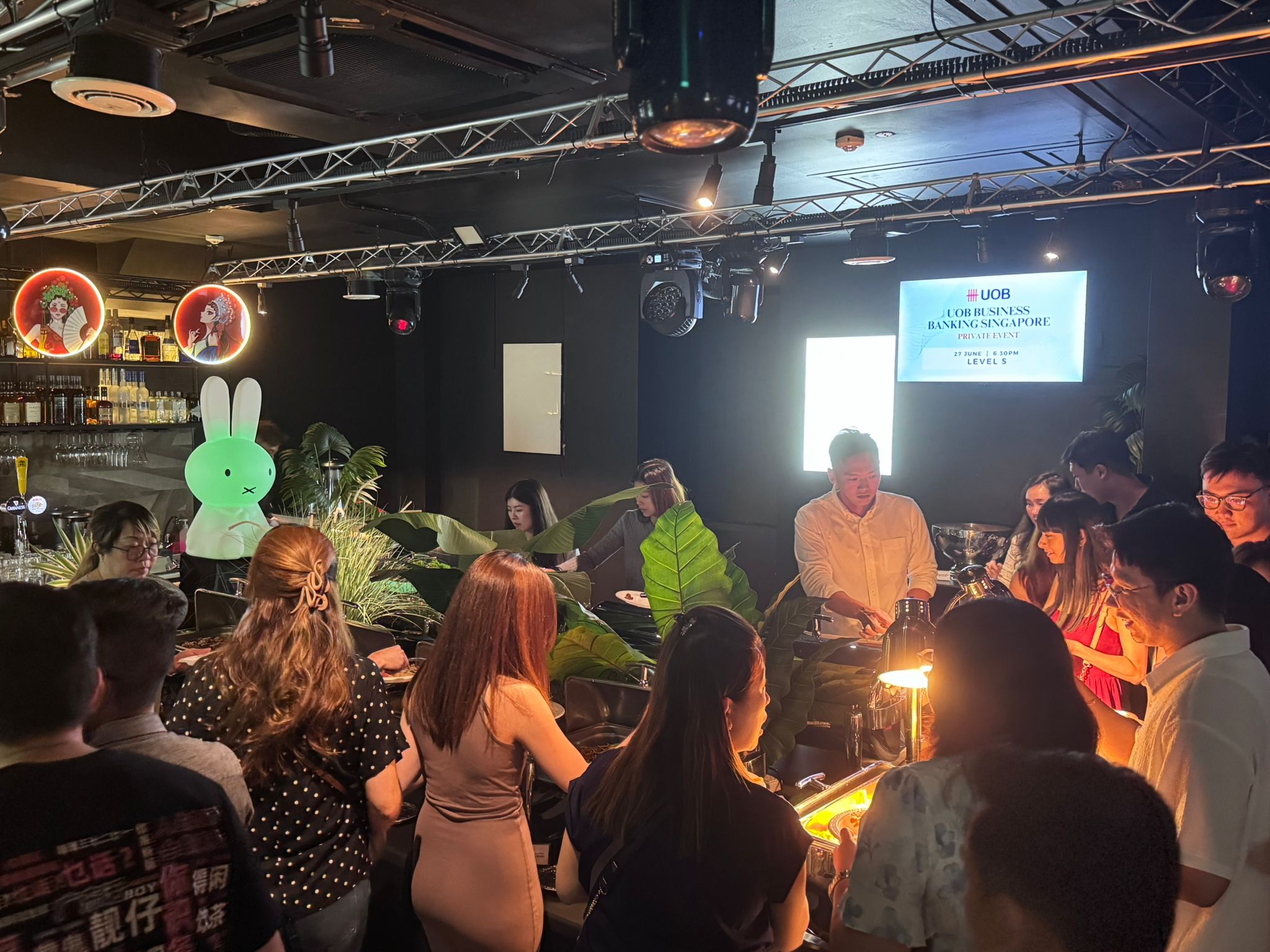 People gathered in a dimly lit room with a DJ playing music on a turntable.