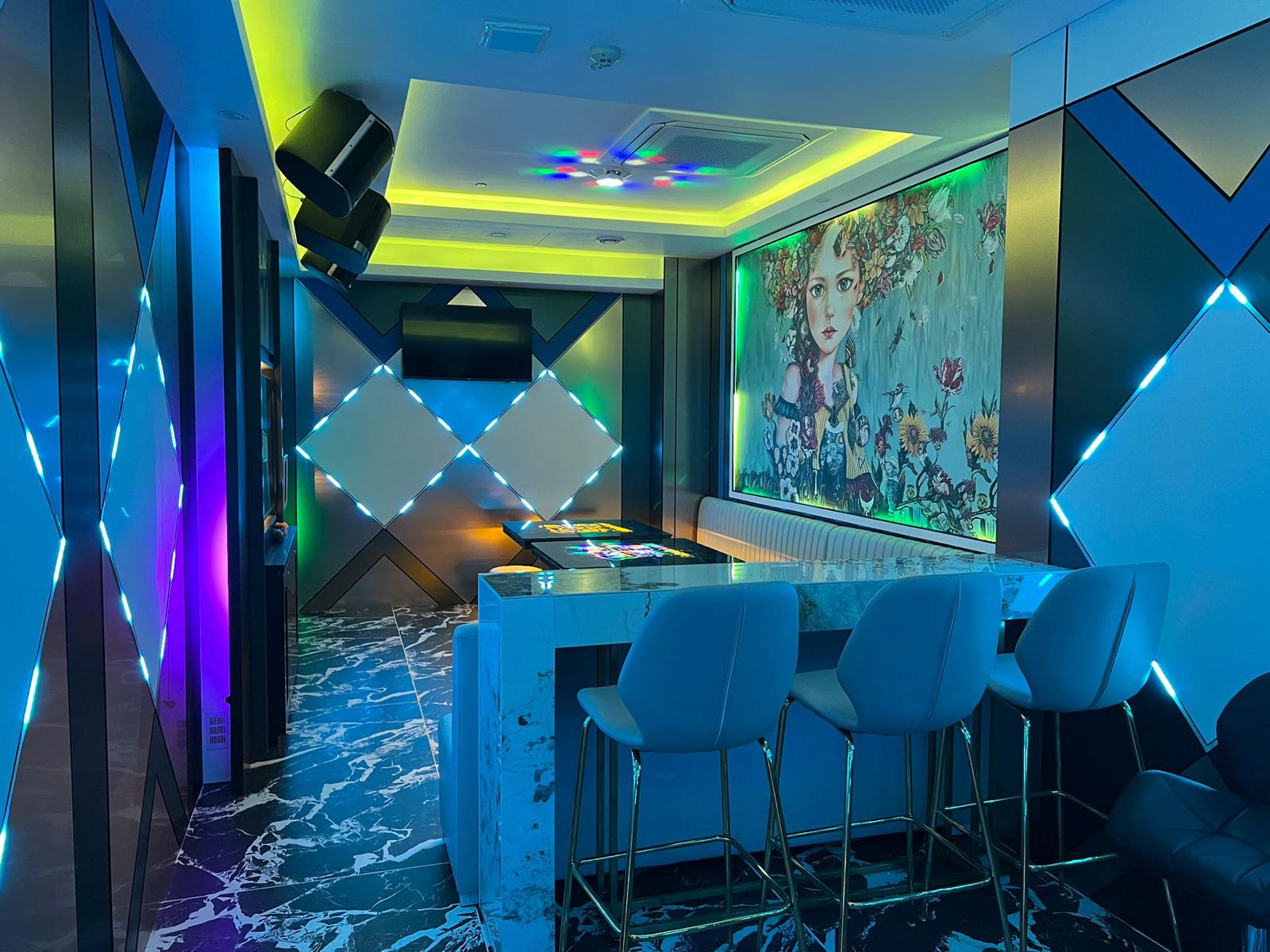 Modern bar interior with blue chairs and a colorful wall art piece in Clarke Quay.