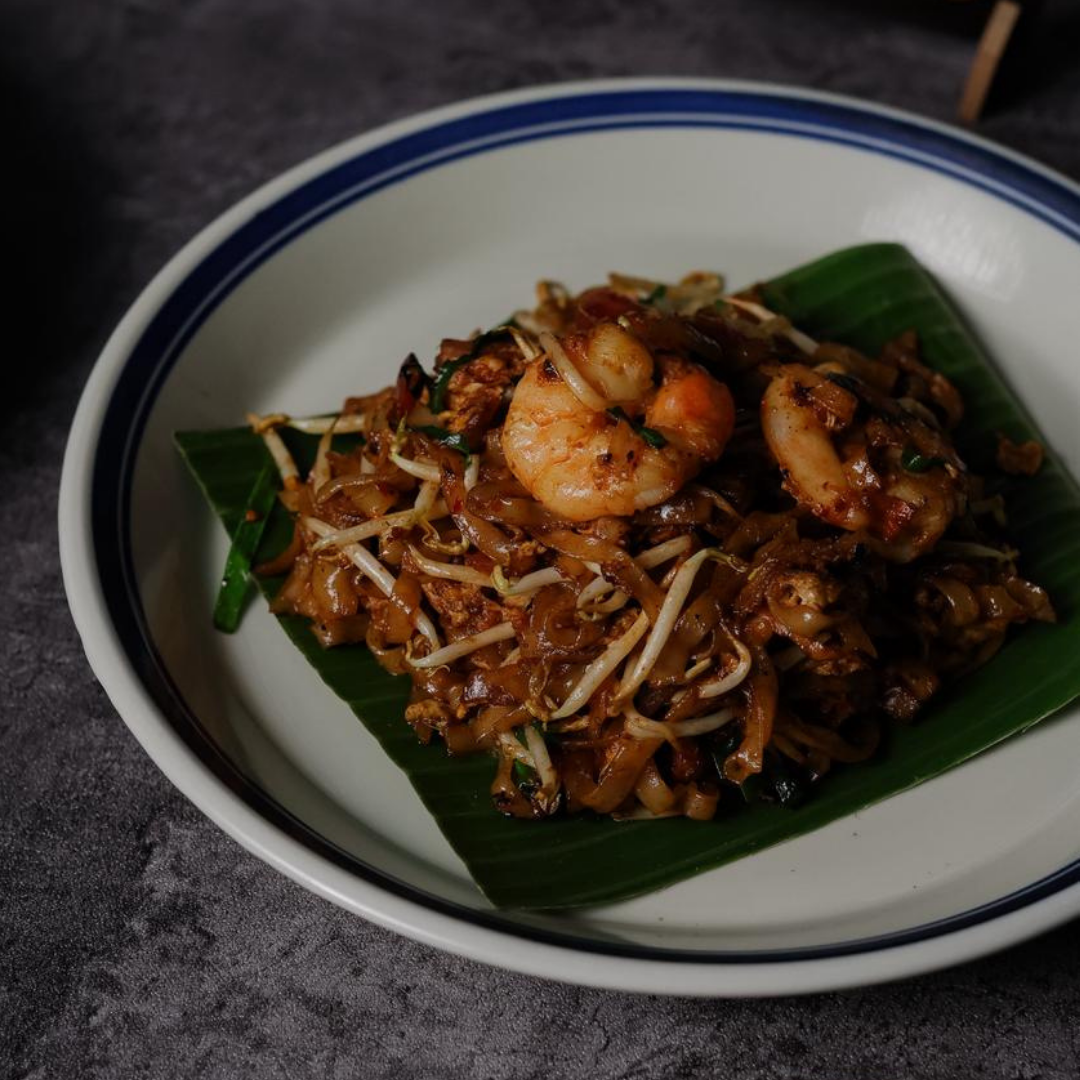 Plated dish of noodles with shrimp on a dark surface