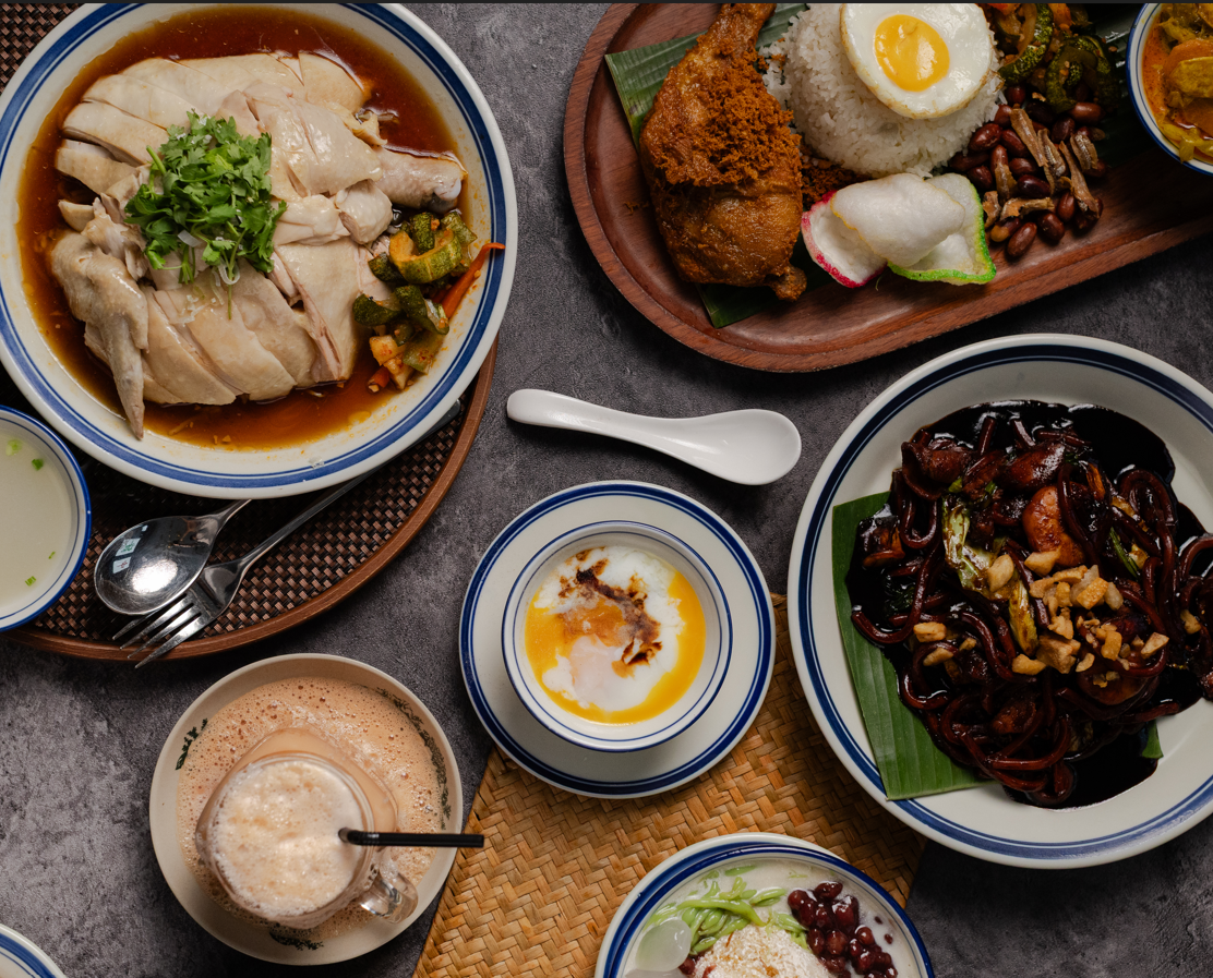 Assorted Nanyang dishes including drinks, noodles, and rice on a table.