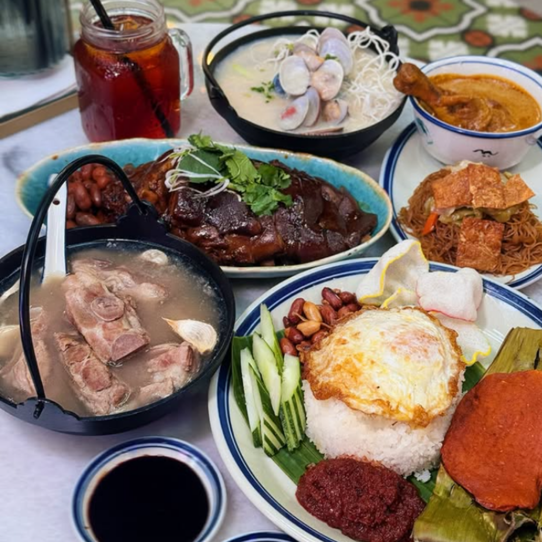 Assorted Nanyang dishes including soup, noodles, and rice on a table.